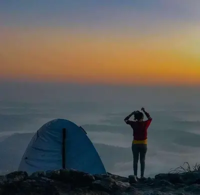 a person standing on top of a mountain near a tent at Wayanad Camping in Ambalavayal