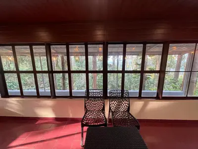two chairs sitting in front of a room with windows at Wayanad Camping in Ambalavayal