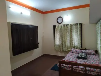 a bedroom with a bed and a clock on the wall at Roopa Studio in Mysore