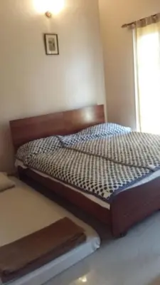 a bedroom with a bed with a wooden headboard and a window at Mulberry Bay Serviced Apartments in Mysore