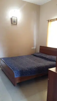 a bedroom with a bed in a room with a window at Mulberry Bay Serviced Apartments in Mysore