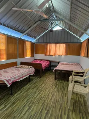 a room with two beds and a chair in it at Nanavu Farmhouse in Māla