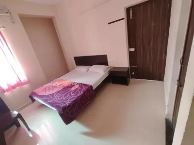a small bedroom with a bed and a wooden door at Union Rooms in Coimbatore