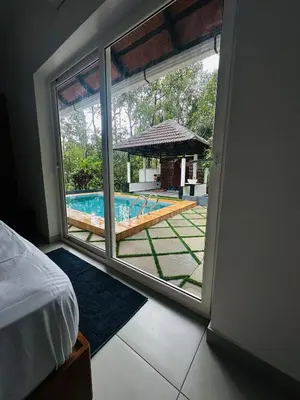 a bedroom with a view of a swimming pool through a window at ThunderHill by Casablanca - A Premium Pool Villa in Meenangadi