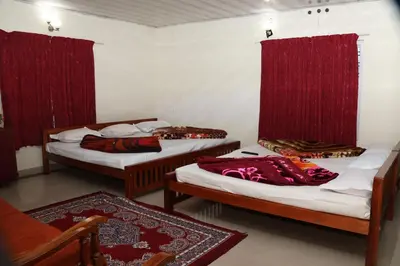 two beds in a room with red curtains at GEE VEE Home Stay in Munnar