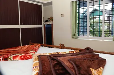 a bedroom with a bed and two windows at GEE VEE Home Stay in Munnar