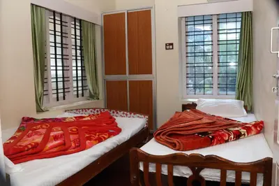 two beds sitting in a room with windows at GEE VEE Home Stay in Munnar