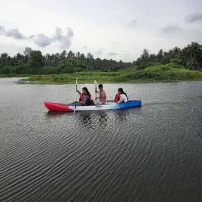 three people in a kayak on a body of water at Dream nest beach house Resort with private beach entrance in Trichūr
