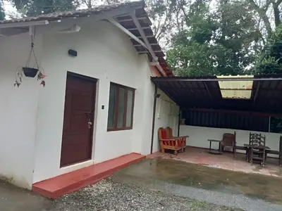 a small white house with a red door at Coorg Mystere Luxury Home Stay in Madikeri
