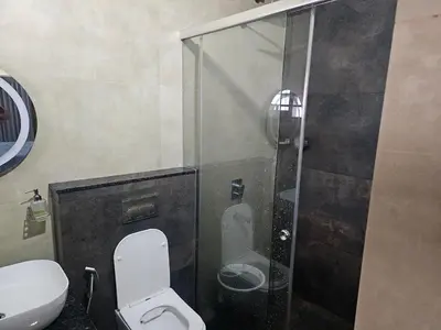 a bathroom with a toilet and a glass shower at Dreams Premium Villa in Kozhikode