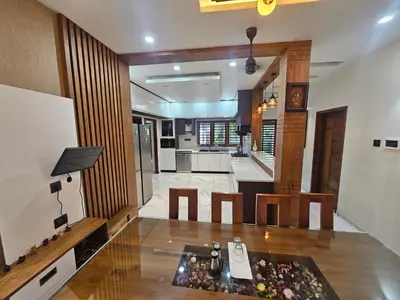 a living room with a table and a kitchen at Dreams Premium Villa in Kozhikode