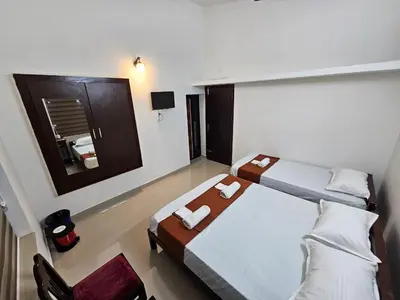 a large room with two beds and a mirror at Guruvayur Nest Homestay in Guruvāyūr