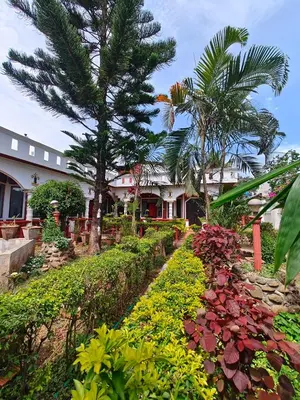a house with a garden with flowers and trees at Nasmat Resort in Masinagudi