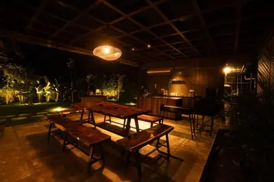 a room with wooden tables and benches and a piano at Vanantara - Riverside Eco Retreat in Ernakulam