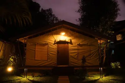 a house with a lit up door in a yard at night at Vanantara - Riverside Eco Retreat in Ernakulam