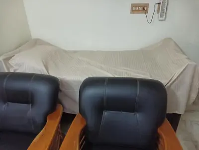 a bed with two chairs in front of a bed at Shield Guest Accommodation in Pudunagaram