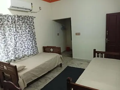 a bedroom with two beds and a window with a curtain at Shield Guest Accommodation in Pudunagaram