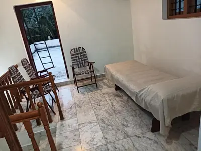 a room with chairs and a bed and a window at Shield Guest Accommodation in Pudunagaram