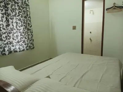 a white bed in a room with a painting on the wall at Shield Guest Accommodation in Pudunagaram