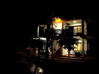 a lit up building with trees in front of it at Coorg Heights in Madikeri