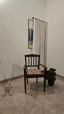 a wooden chair sitting in a room with a curtain at The Horalahalli House in Mysore