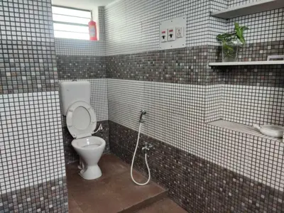 a tiled bathroom with a toilet and a sink at The Horalahalli House in Mysore