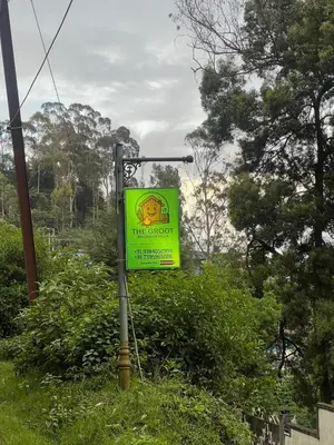 a yellow sign on a pole next to some bushes at The Groot in Ooty