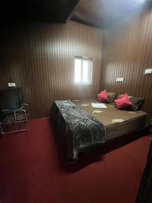 a bedroom with a bed with red pillows and a window at The Groot in Ooty