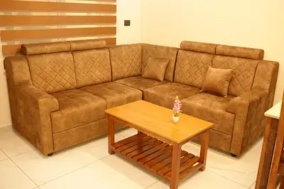 a brown couch in a living room with a coffee table at Joen homes apartment in Alwaye
