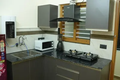 a kitchen with a stove and a microwave on a counter at Joen homes apartment in Alwaye