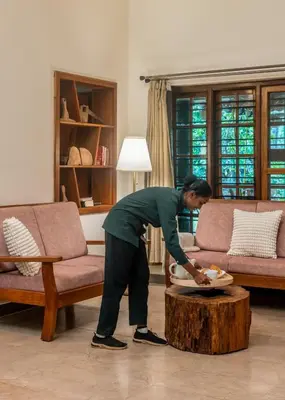 a man standing in a living room with a table at Chetty's Mane by Raho - Estate-View Heritage Stay in Siddapur