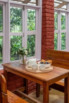 a wooden table with a tray of food on it at Chetty's Mane by Raho - Estate-View Heritage Stay in Siddapur
