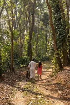 a man and a girl walking down a dirt road with a bike at Chetty's Mane by Raho - Estate-View Heritage Stay in Siddapur