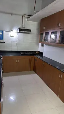 a kitchen with wooden cabinets and a black counter top at Cityscape Residence and Homestay Tirupur in Tiruppūr