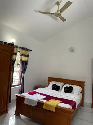 a bedroom with a bed with a ceiling fan at Midnight Oasis Wayanad in Meenangadi