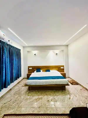 a bedroom with a bed and blue curtains at CLR Homestay & Villa in Kushālnagar