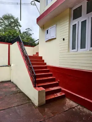 a house with a red staircase next to a building at Kalanja Greens Nilagiri Villa in Ooty