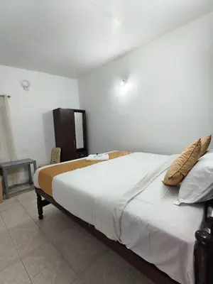 a bedroom with a large bed with white sheets and pillows at Kalanja Greens Nilagiri Villa in Ooty