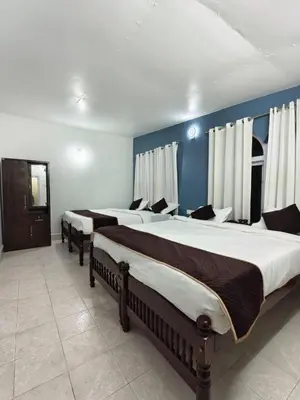 a group of four beds in a room at Kalanja Greens Nilagiri Villa in Ooty