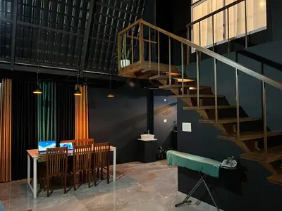 a staircase in a room with a table and chairs at The Stellar By Stayzi in Nilambūr