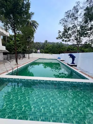 a swimming pool with a man sitting on a surfboard in the water at Haveninn in Athirappilly