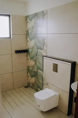 a bathroom with a toilet and a mural of plants at Camplights Stays in Tariyod
