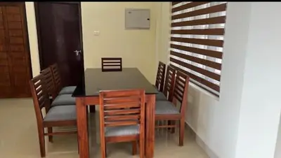 a dining room with a table and wooden chairs at Malayattoor Castle in Kodanad