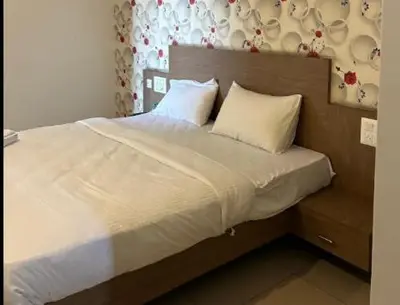 a bed with white sheets and pillows in a bedroom at Hotel Janani Mansion in Mysore