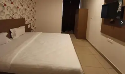a bedroom with a large white bed in a room at Hotel Janani Mansion in Mysore