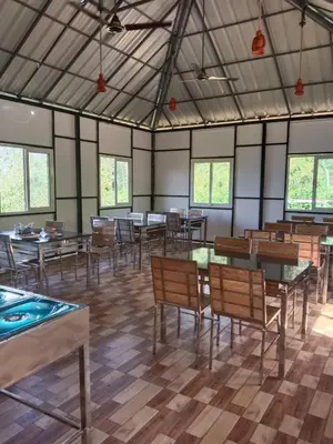 a dining room with tables and chairs and windows at Bhramaram resort in Kanthalloor