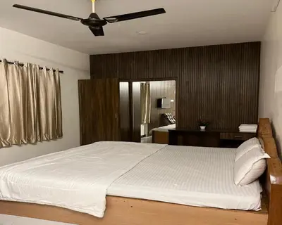 a bedroom with a white bed with a ceiling fan at The Whistling Pine Woods in Varagampadi