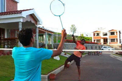 two men playing tennis in front of a net at Western Valley Resorts Ooty in Ooty