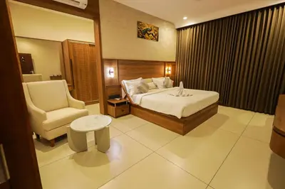 a hotel room with a bed and a chair at Townsquare Residency in Kommeri