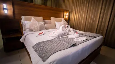 a bed with two swans towels on it at Townsquare Residency in Kommeri